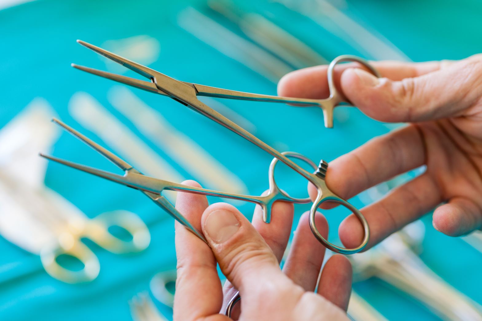 Hands holding two pairs of forceps and comparing them